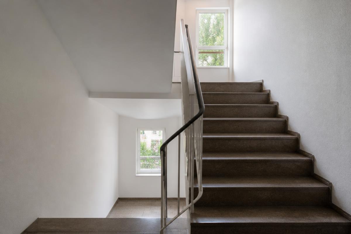 Sauberes Treppenhaus eines Mehrfamilienhauses mit Handlauf und Fenstern